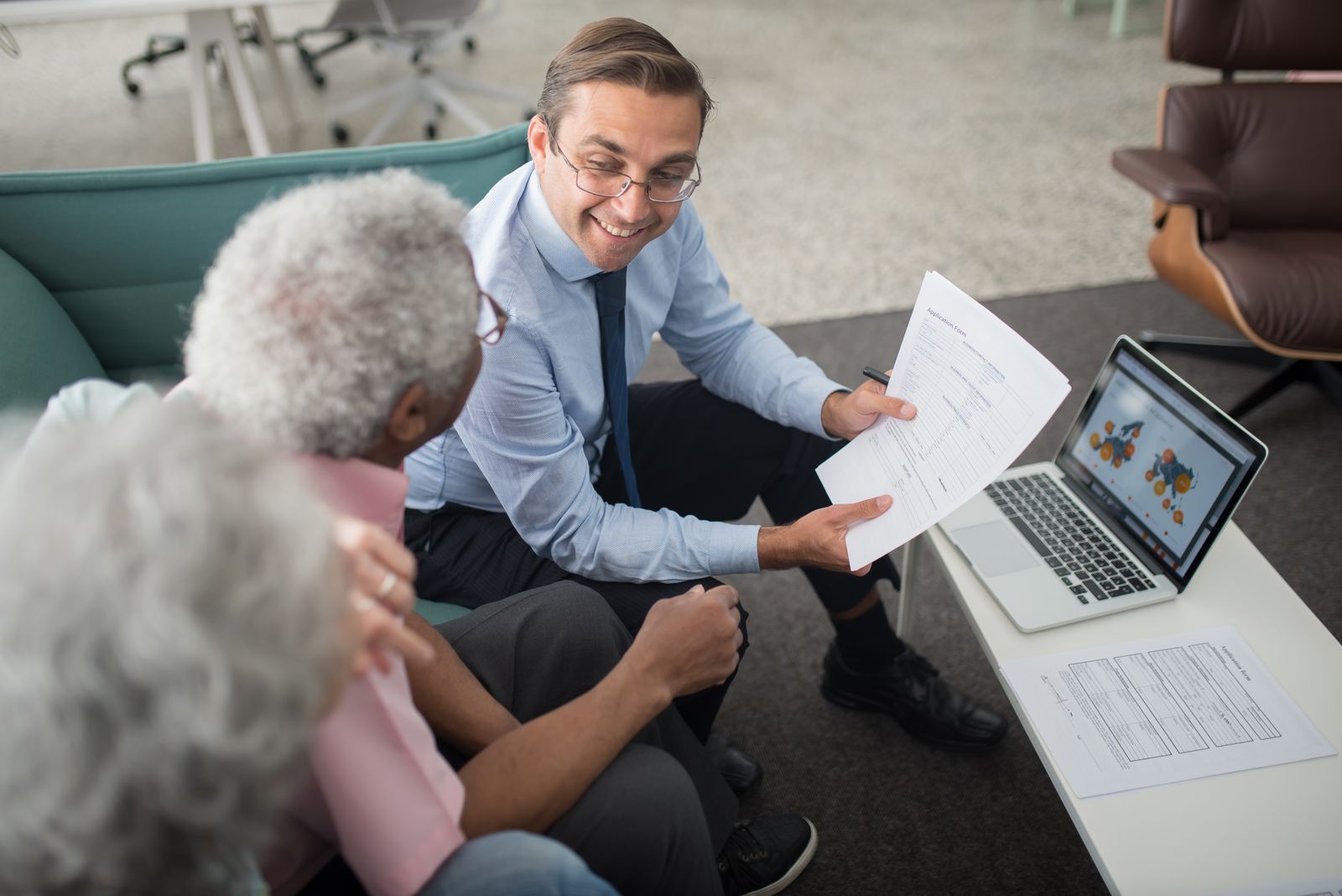 An advisor reviewing documents with a couple beside a laptop