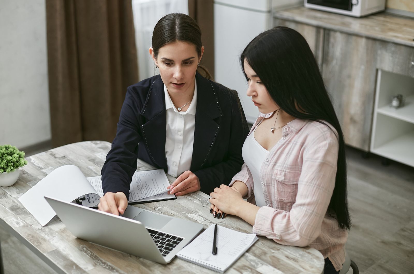 Two colleagues reviewing documents together at a laptop